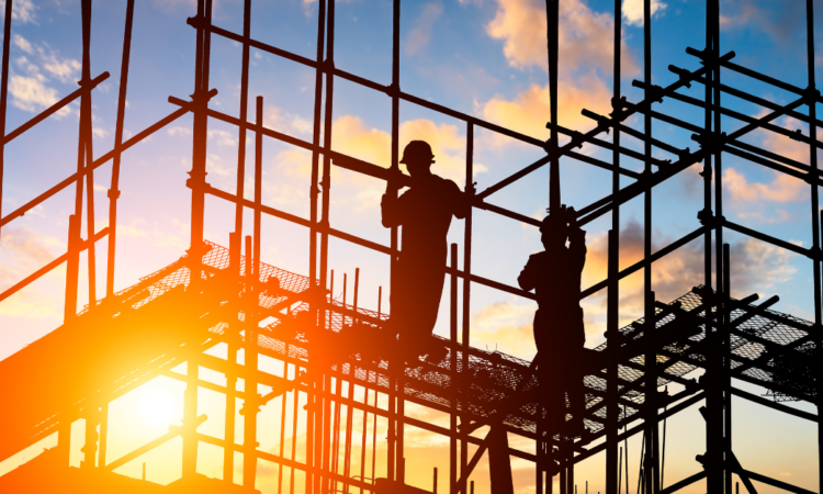 Two men standing on a scaffold with the sun shining through